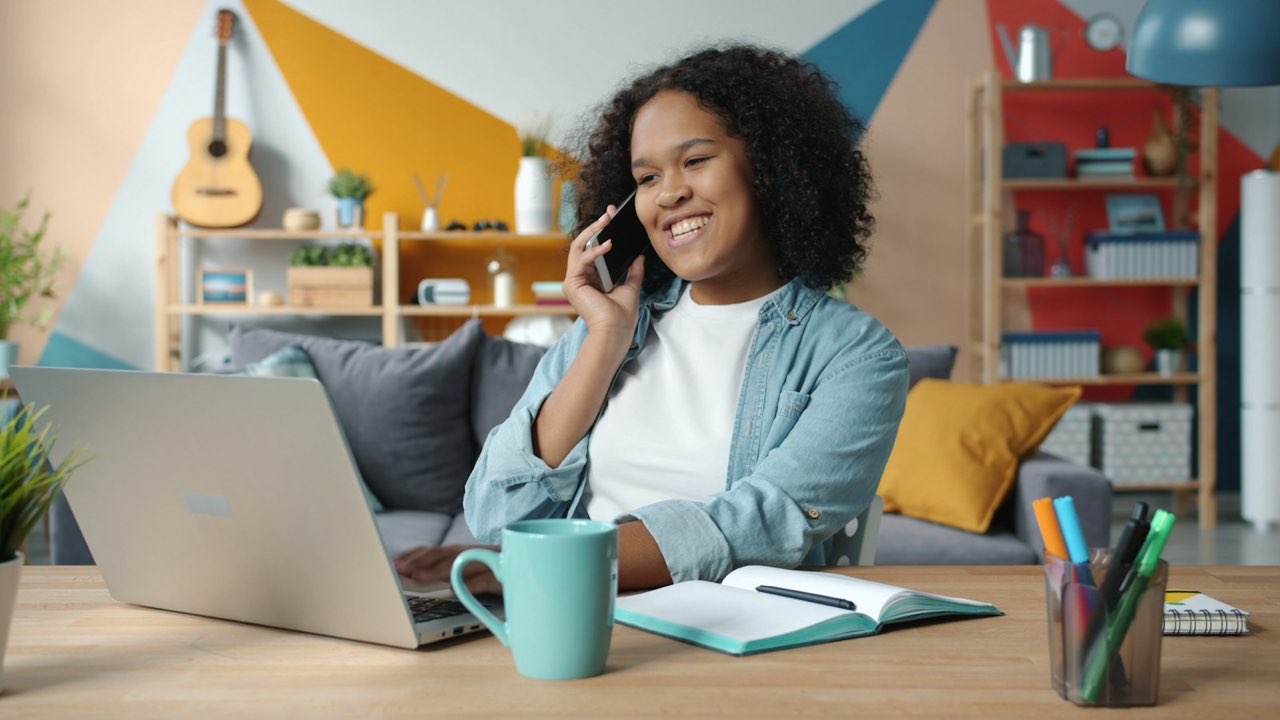 A smiling job seeker on a phone call at her laptop